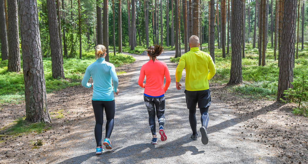 Tre personer joggar i skogen