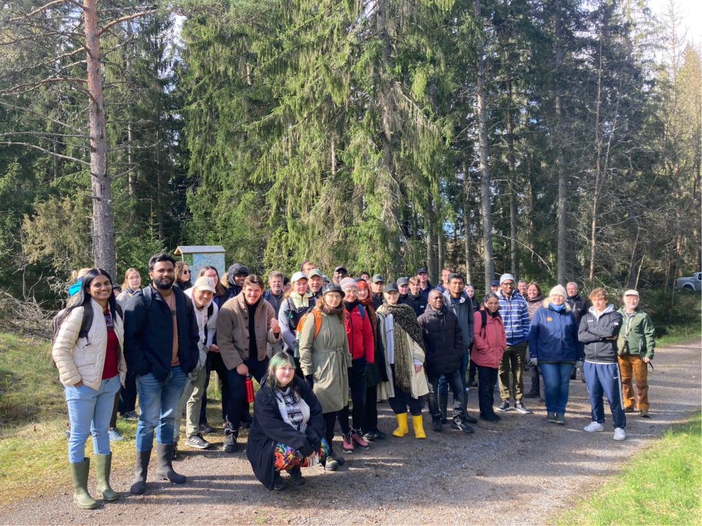 Glada människor på en skogsväg ler mot kameran.