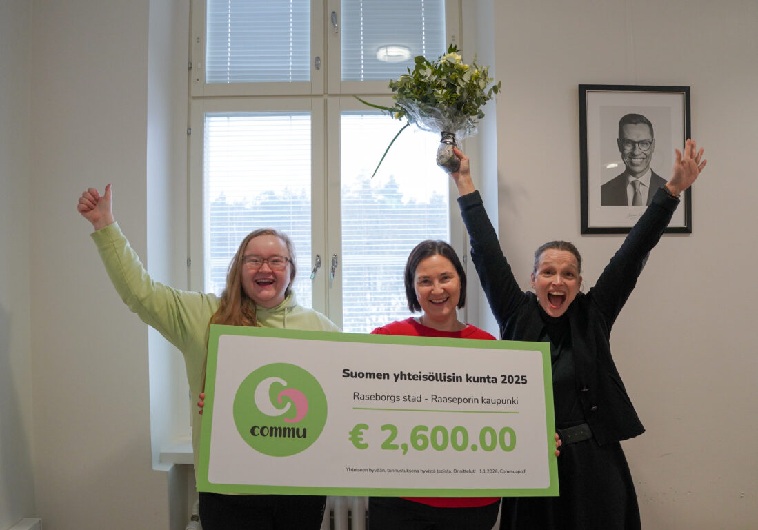 Tre glada personer räcker händerna i luften och håller i en stor check och en blombukett.