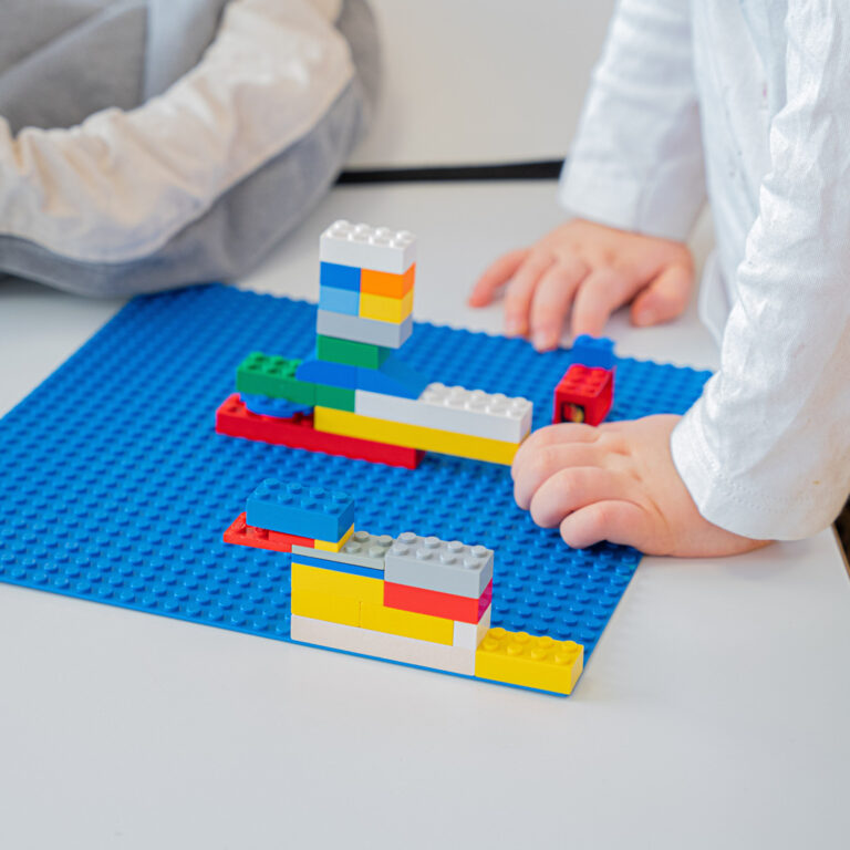 Legoplatta med legoklossar och barnhänder. Lapset rakentavat legopalikoilla.