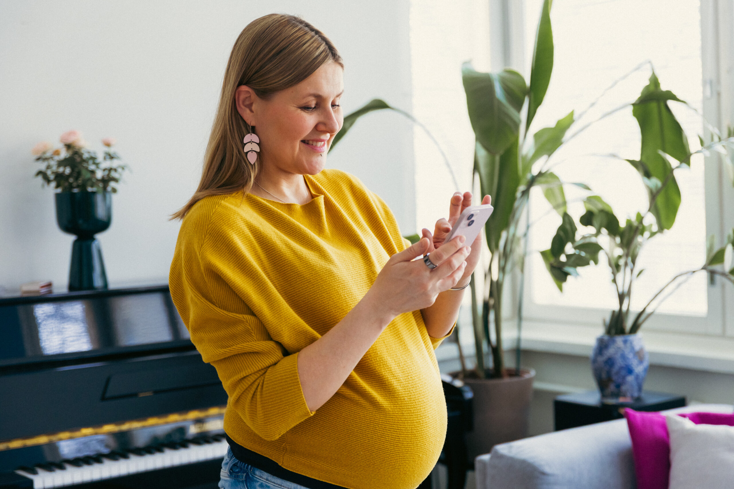 Gravid person tittar på sin telefon. Raskaana oleva henkilö katsoo puhelintaan.